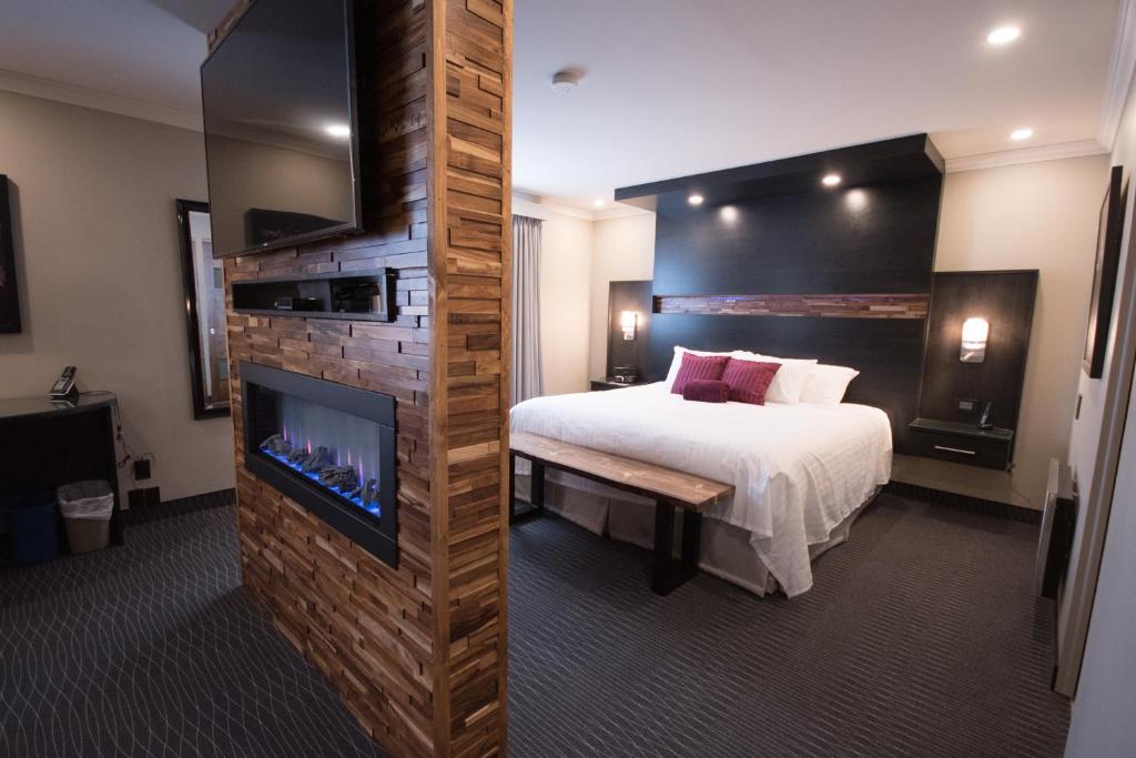 een hotelkamer met een bed, een open haard en een tv bij Hotel des Eskers in Amos