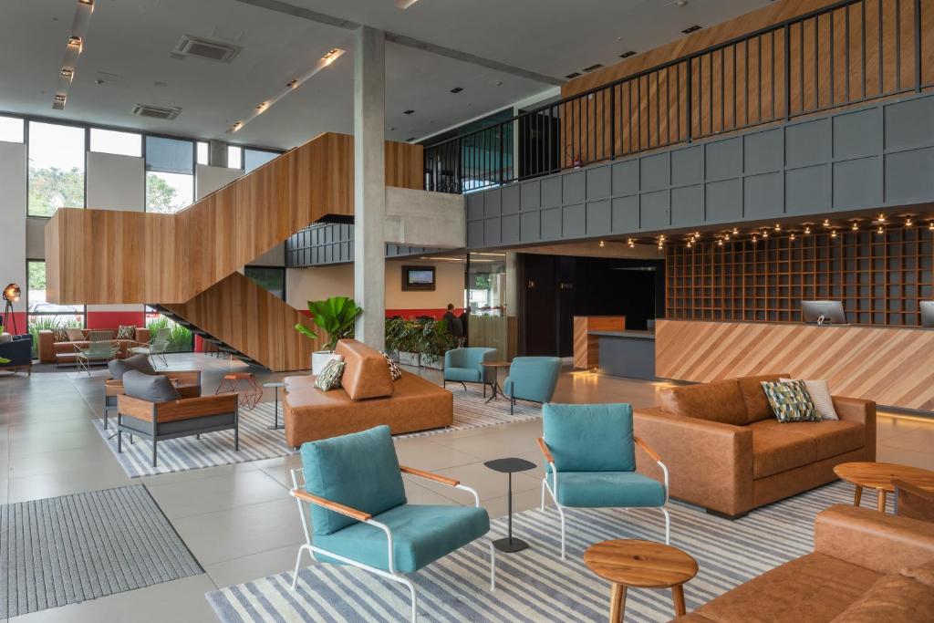 a lobby with couches and chairs and a staircase at Linx Galeão in Rio de Janeiro