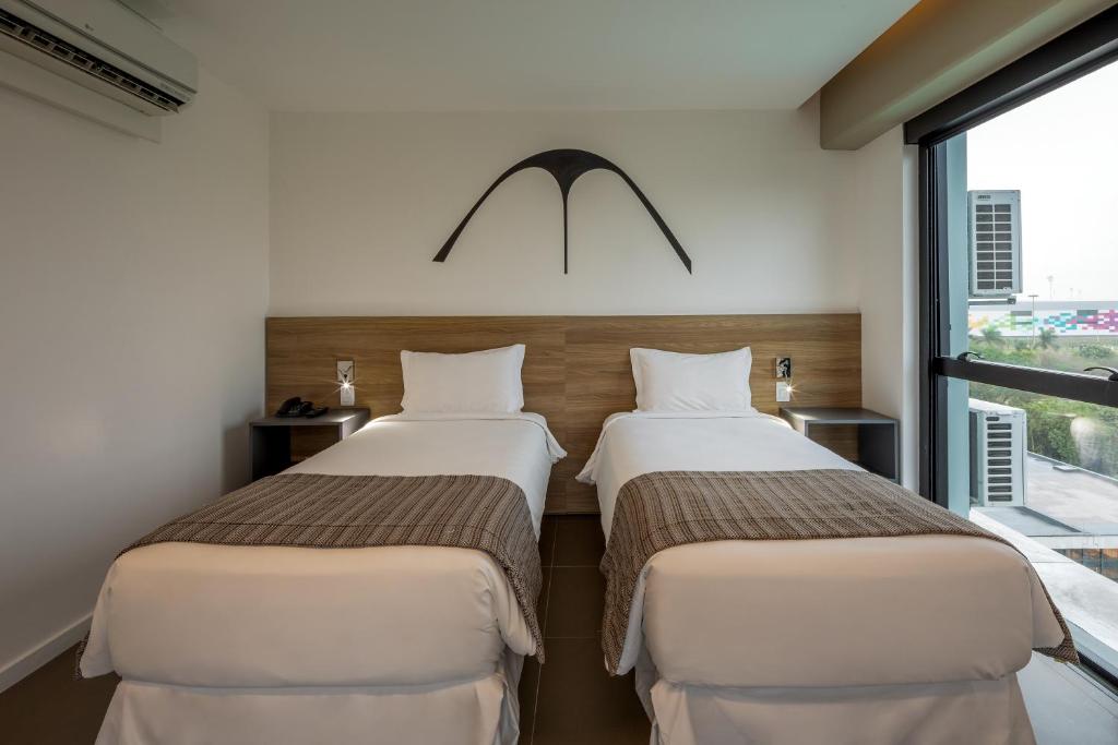 two beds in a room with a window at Linx Galeão in Rio de Janeiro