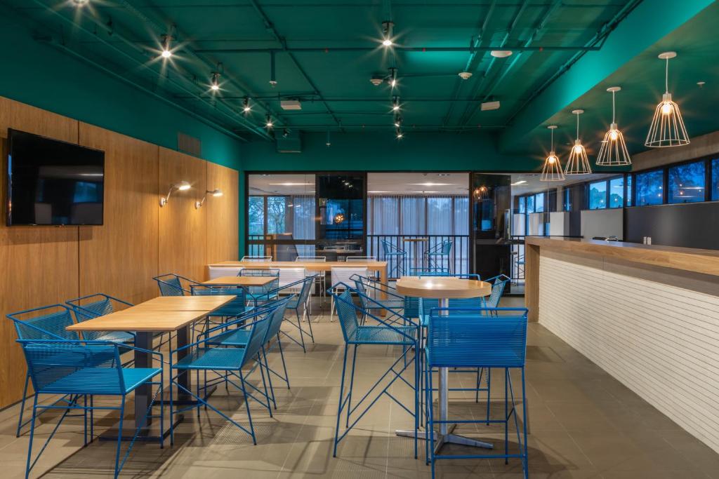 a dining room with tables and blue chairs at Linx Galeão in Rio de Janeiro
