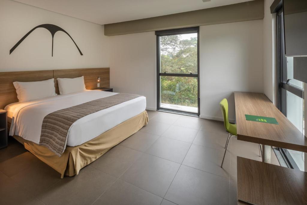 a bedroom with a large bed and a desk at Linx Galeão in Rio de Janeiro
