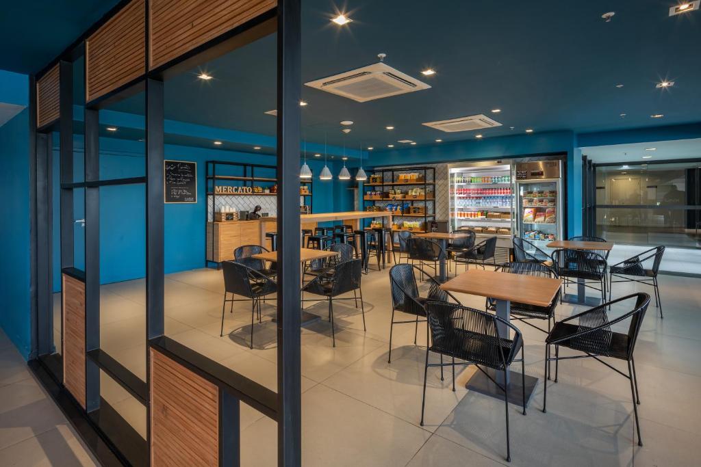 a restaurant with blue walls and tables and chairs at Linx Galeão in Rio de Janeiro
