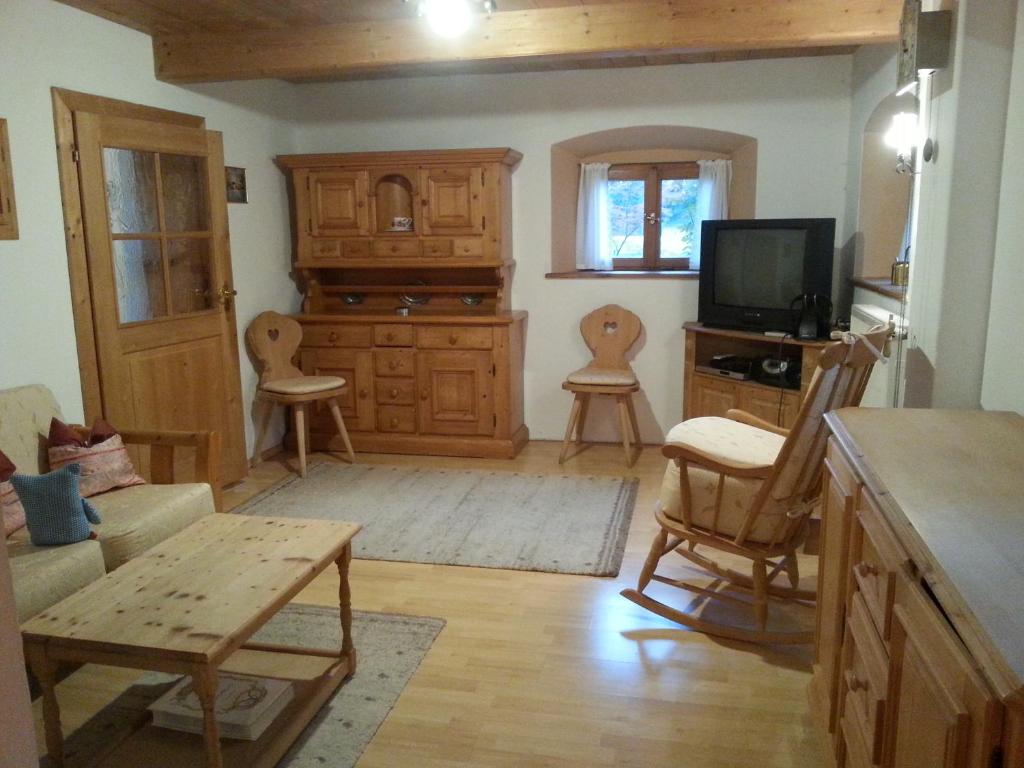 sala de estar con muebles de madera y TV en Ferienhaus Kraihof, Münchner Straße 234, en Gmund am Tegernsee