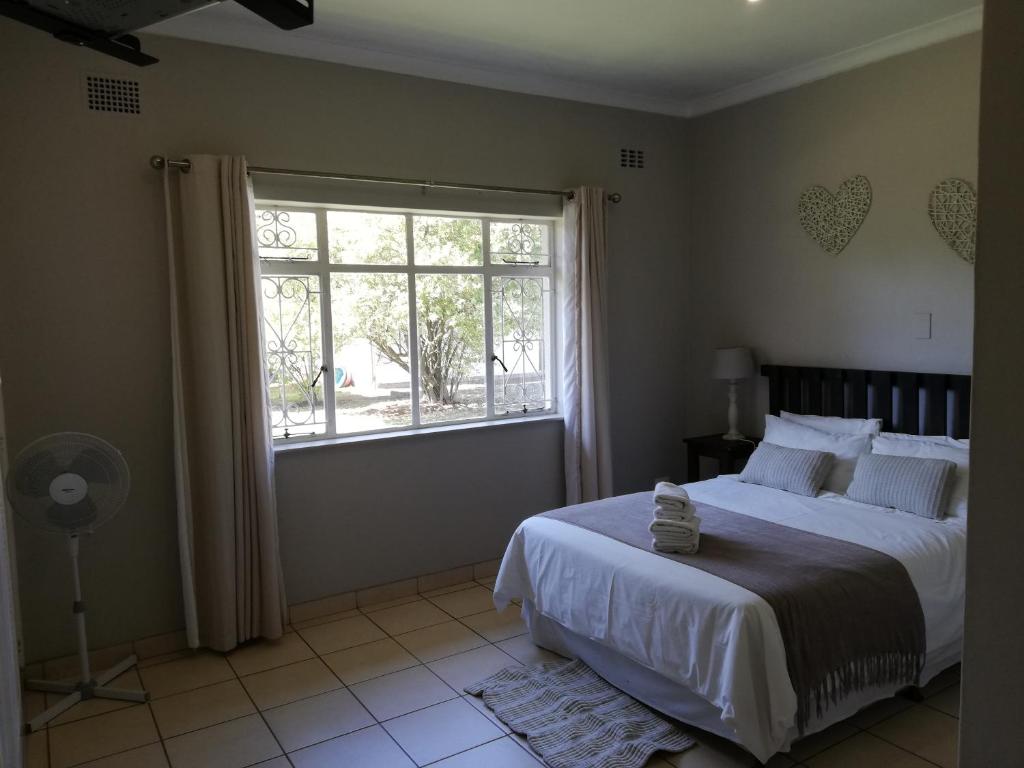1 dormitorio con cama y ventana grande en Abendruhe Guest House, en Eshowe