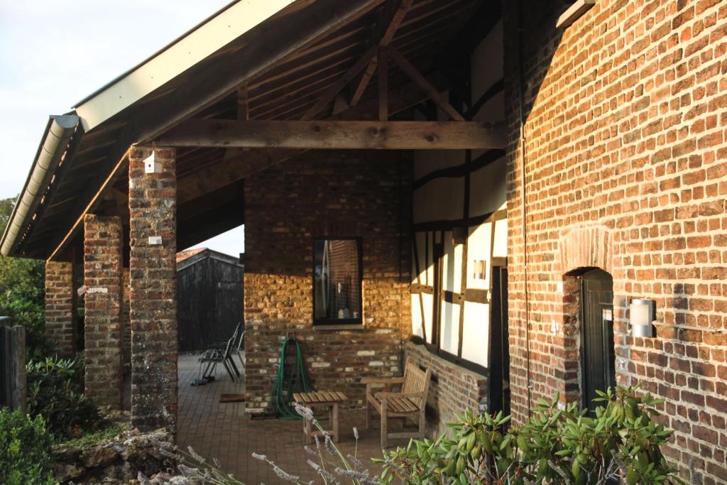 a brick building with a patio with chairs and tables at Hoeve "doodleger" in Vijlen