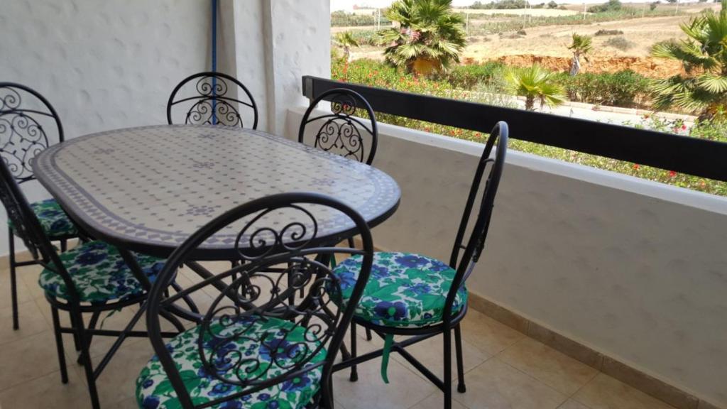 een tafel en stoelen op een balkon met uitzicht op de woestijn bij Asilah Marina Golf Appart in Asilah