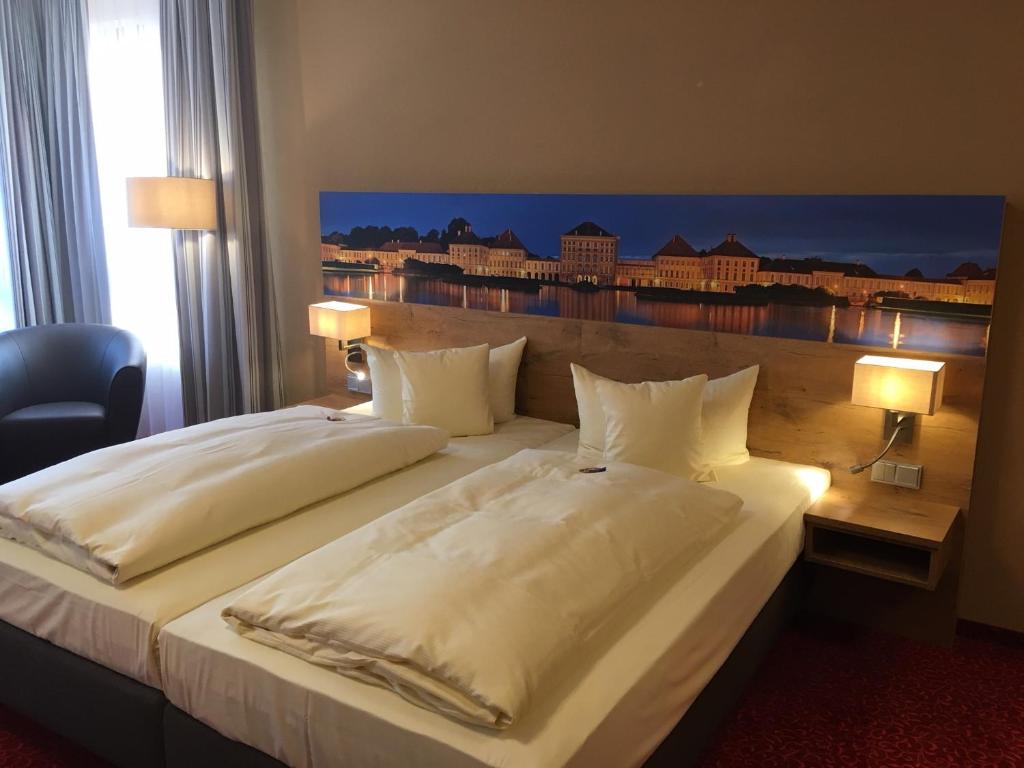 プラネックにあるパークホテル ライザーの白い枕2つが備わるホテルルームの大型ベッド1台