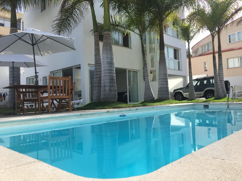 a swimming pool with a table and an umbrella at White House Suite in Los Llanos de Aridane
