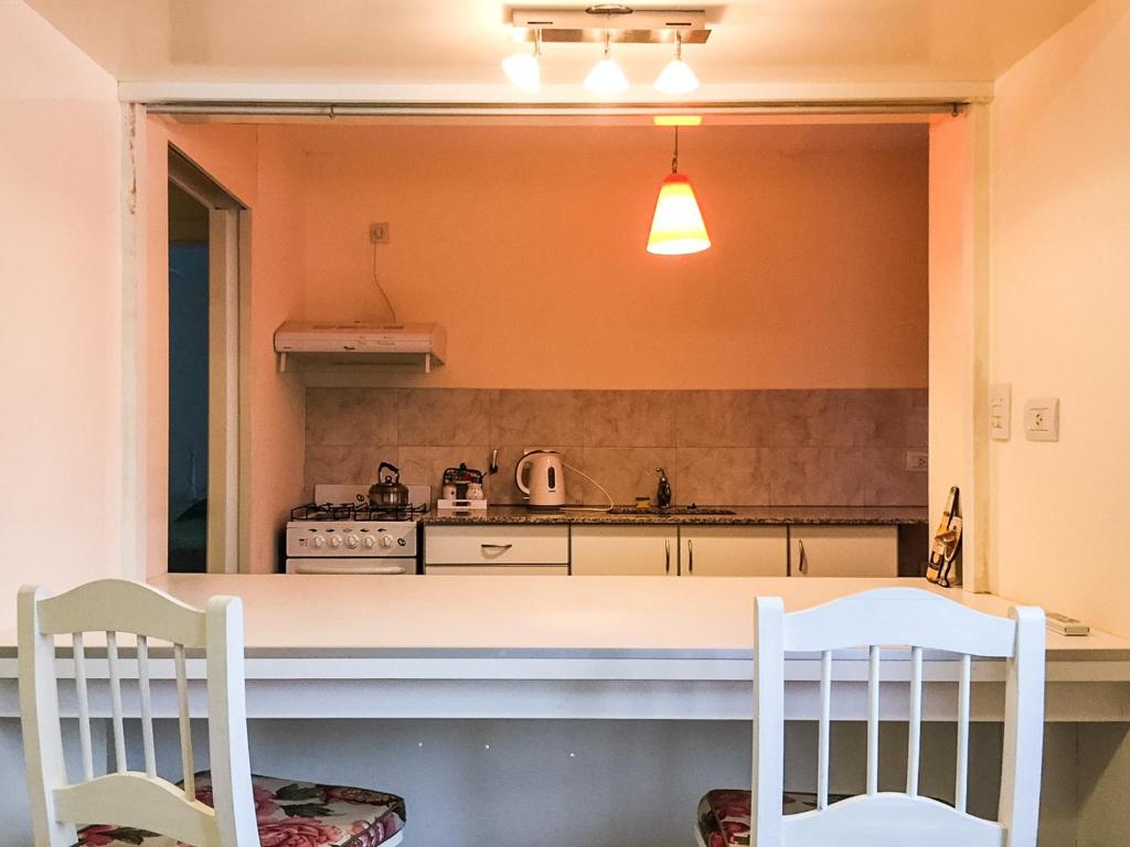 a kitchen with two white chairs and a counter at Departamento Temporario Bahia Blanca in Bahía Blanca