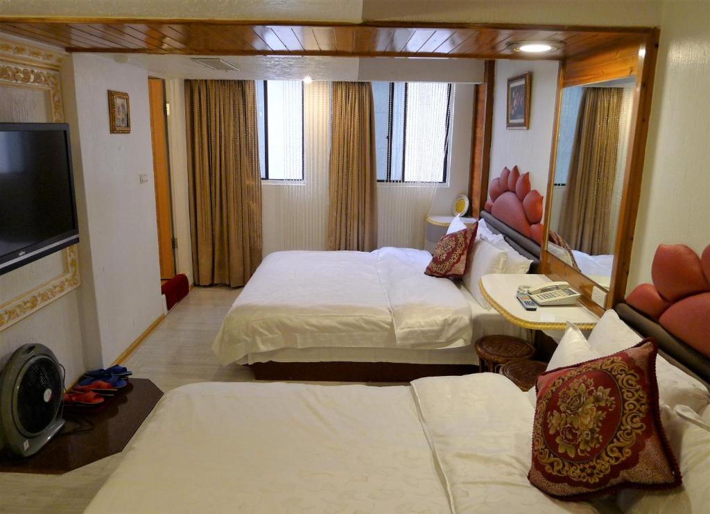 Habitación de hotel con 2 camas y TV de pantalla plana. en Aloha Hotel en Keelung
