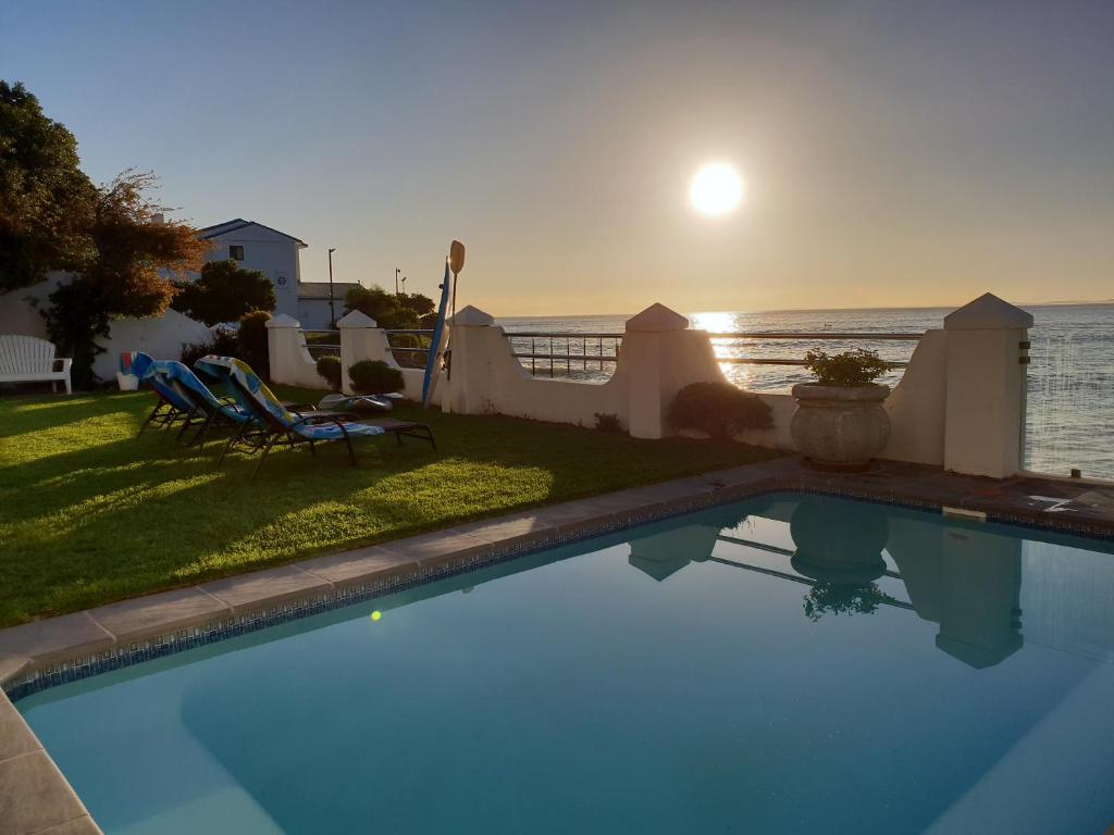 a swimming pool with a view of the ocean at sunset at Westbank Private Beach Villa, 4 Bedrooms, Private pool, on the Beach! in Gordonʼs Bay