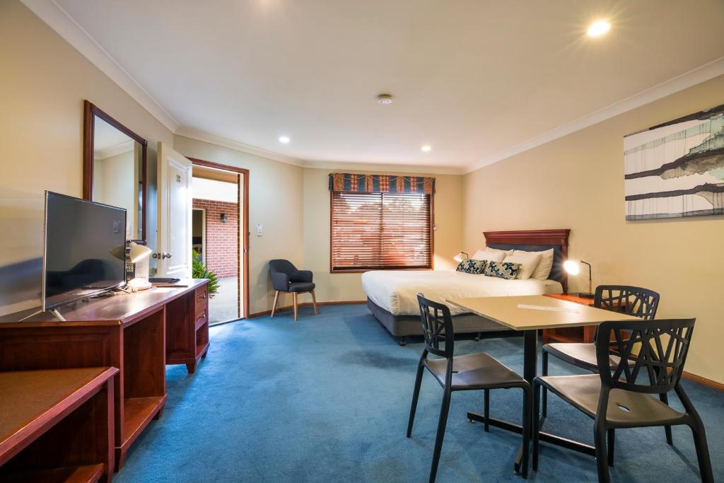 Nightcap at Federal Hotel Toowoomba في توومبا: غرفة فندقية بسرير وطاولة وكراسي