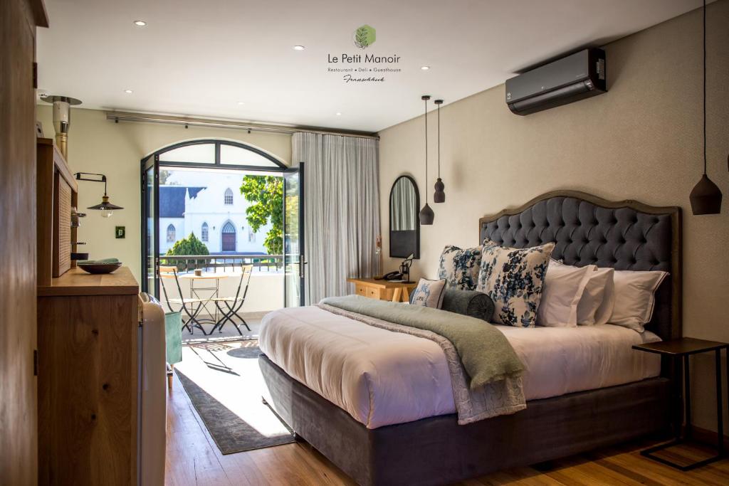 a bedroom with a large bed and a balcony at Le Petit Manoir Franschhoek in Franschhoek