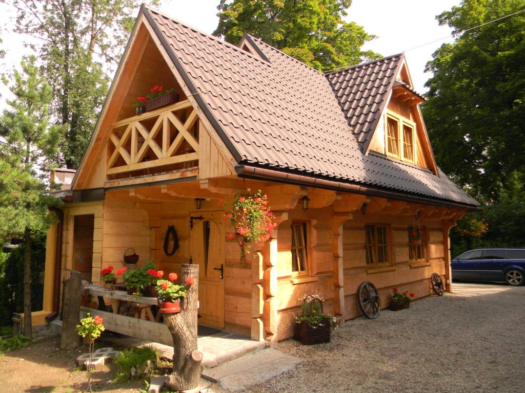 una pequeña casa de madera con flores delante en Góralski Domek Jasinek, en Zakopane