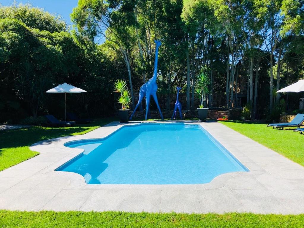 a swimming pool with a statue of a giraffe in a yard at The Tarragon in Hout Bay