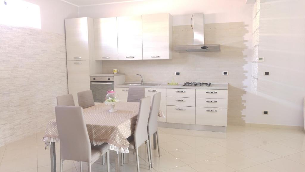 cocina con mesa, sillas y armarios blancos en Guest House " Chilli & Chocolate", en Pompeya