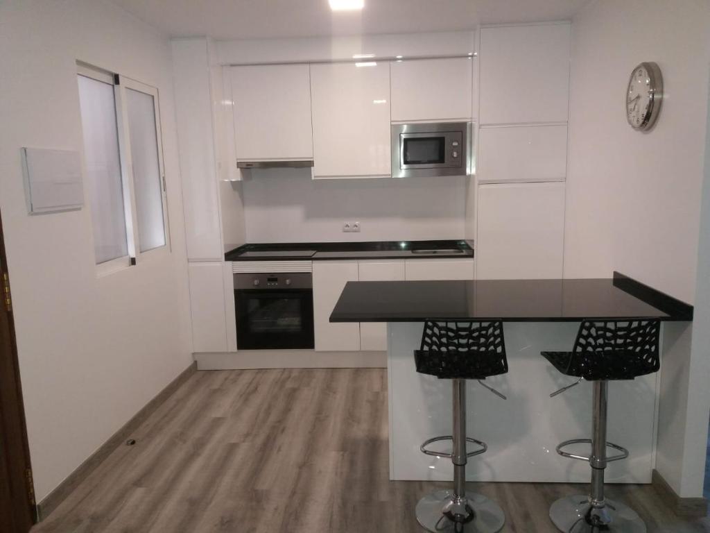 a kitchen with white cabinets and a black counter top at Jazmines in Santiago de la Ribera