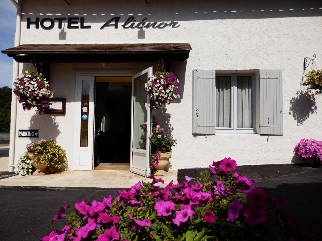 un bâtiment d'alliance hôtelière avec des fleurs devant lui dans l'établissement Hotel Alienor, à Brantôme