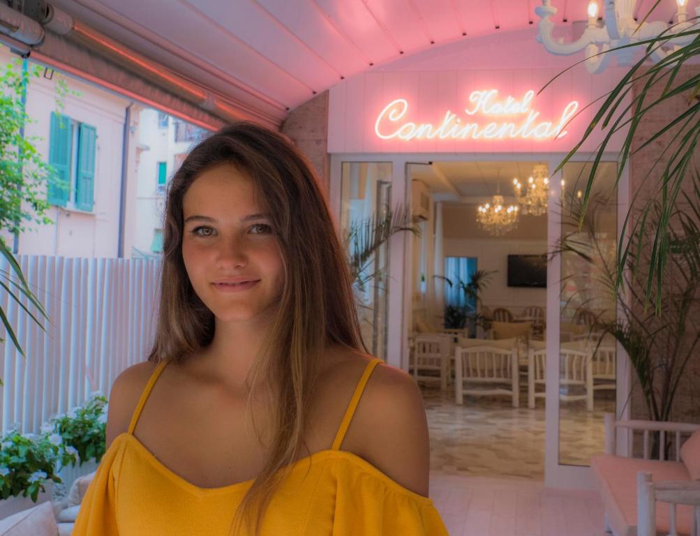 Una donna con un vestito giallo davanti a un ristorante di Hotel Continental a Pietra Ligure