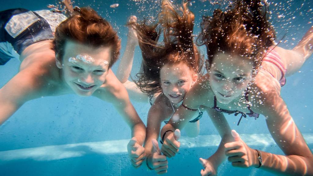 a group of three children swimming in the water at Palladium de Champéry in Champéry