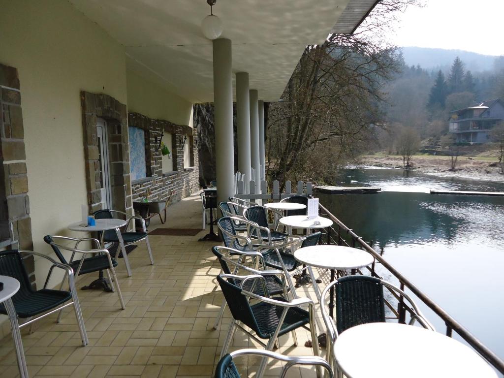 a row of tables and chairs on a patio with a river at Hotel Dirbach Plage in Dirbach