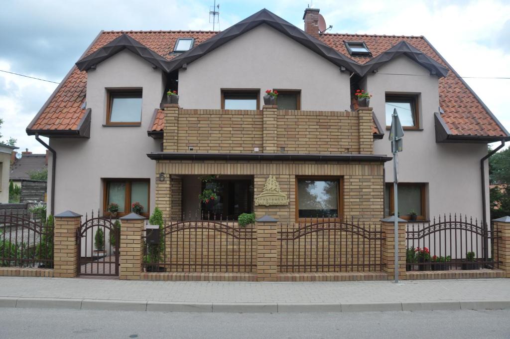 a house with a fence in front of it at Apartament Pod Świerkami in Olecko