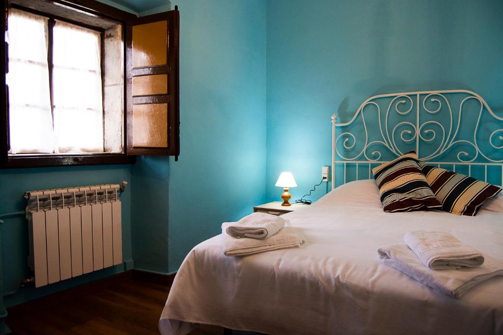 ein blaues Schlafzimmer mit einem Bett mit Handtüchern darauf in der Unterkunft Casa Justa in San Martín de Luiña