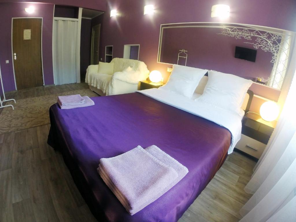a hotel room with a large bed with a purple blanket at Guest House Miya Domodedovo in Domodedovo