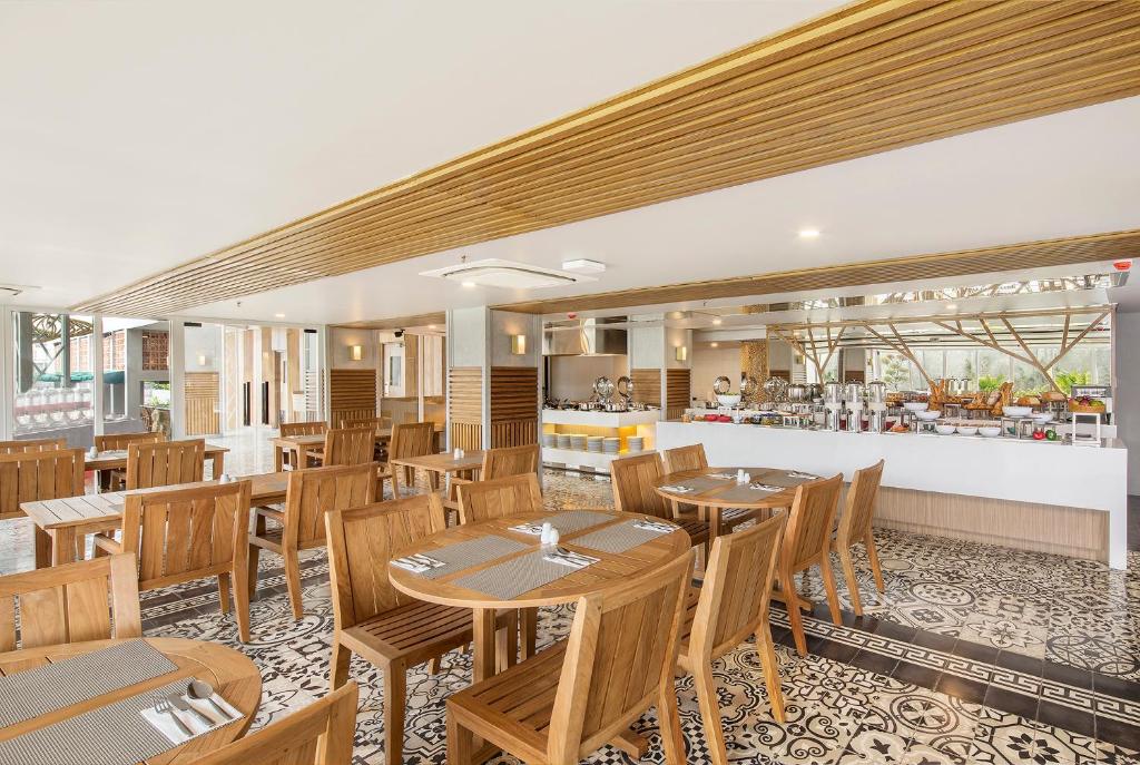 a restaurant with wooden tables and chairs and a counter at Eastin Ashta Resort Canggu in Canggu