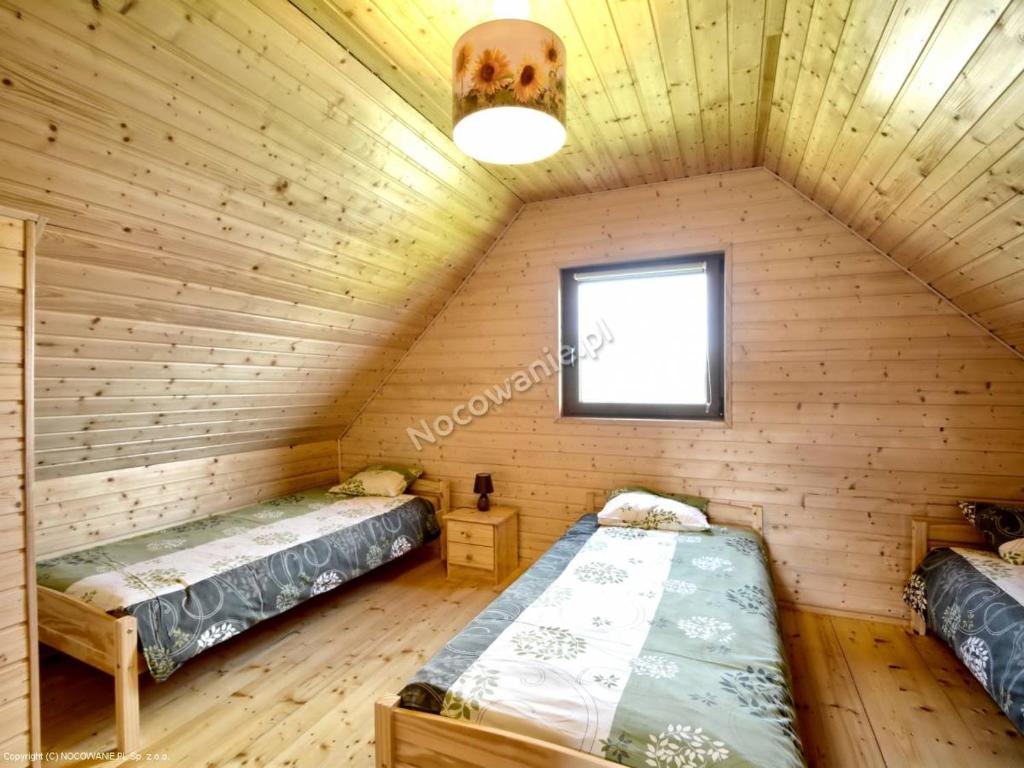 Cozy attic bedroom with three single beds, wooden paneling and soft overhead lighting.