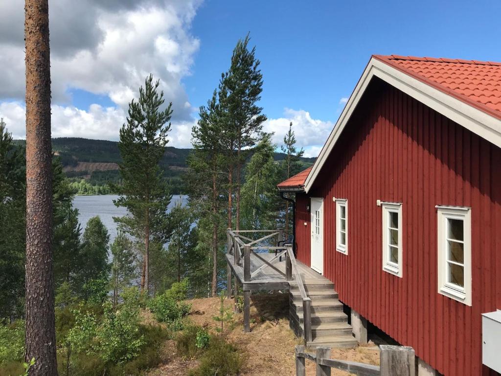 a red building with a staircase next to a tree at Chalet in Torsby Municipality Middle with Sauna in Gunsjögården