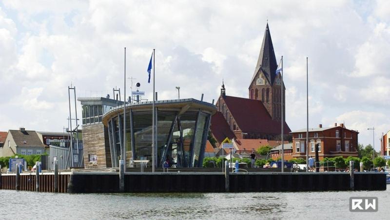 a building with a clock tower next to a body of water at Ostseeferien in Barth; FeWo "Korls Hüsung" in Barth