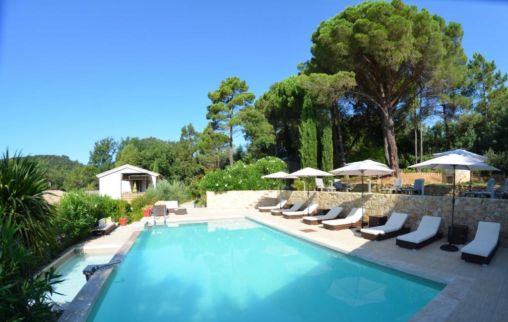 a swimming pool with lounge chairs and umbrellas at Ancie in Grimaud