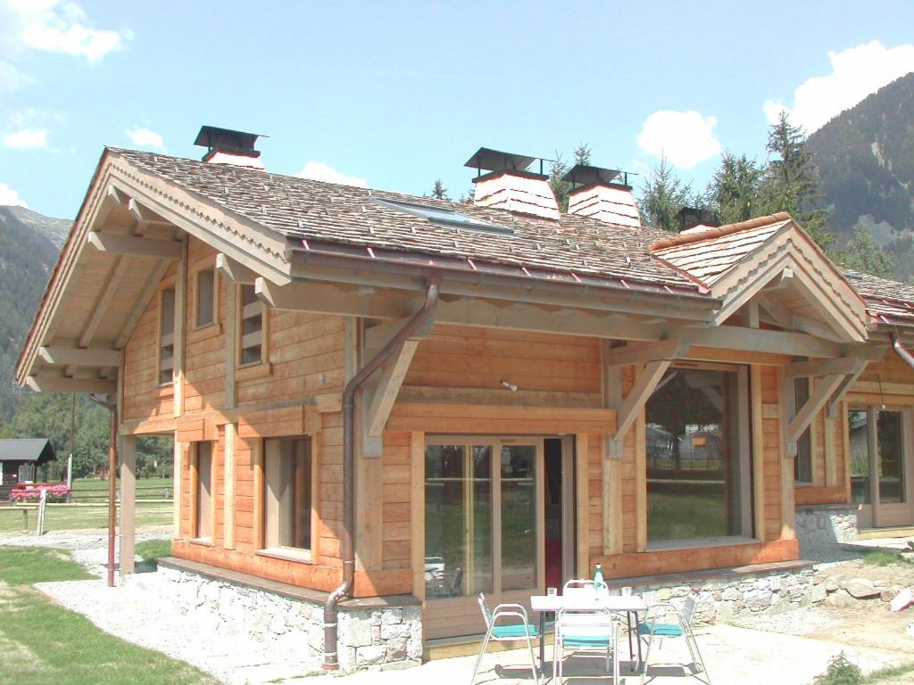 una cabaña de madera con una mesa y sillas frente a ella en Chalet Bois - Chamonix, en Chamonix-Mont-Blanc