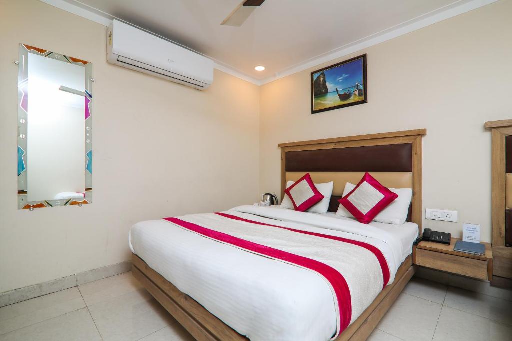 a bedroom with a large white bed with red pillows at Hotel Amar International in New Delhi