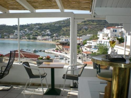 balcón con mesa, sillas y vistas al agua en Adonis Guesthouse, en Batsi