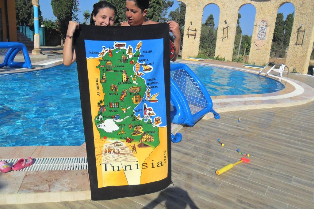 a sign with a map of tunisia next to a pool at Ben's House in El Maamoura