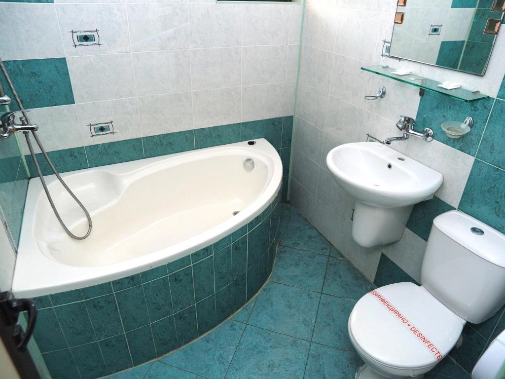 a bathroom with a tub and a toilet and a sink at Eos Hotel in Vidin