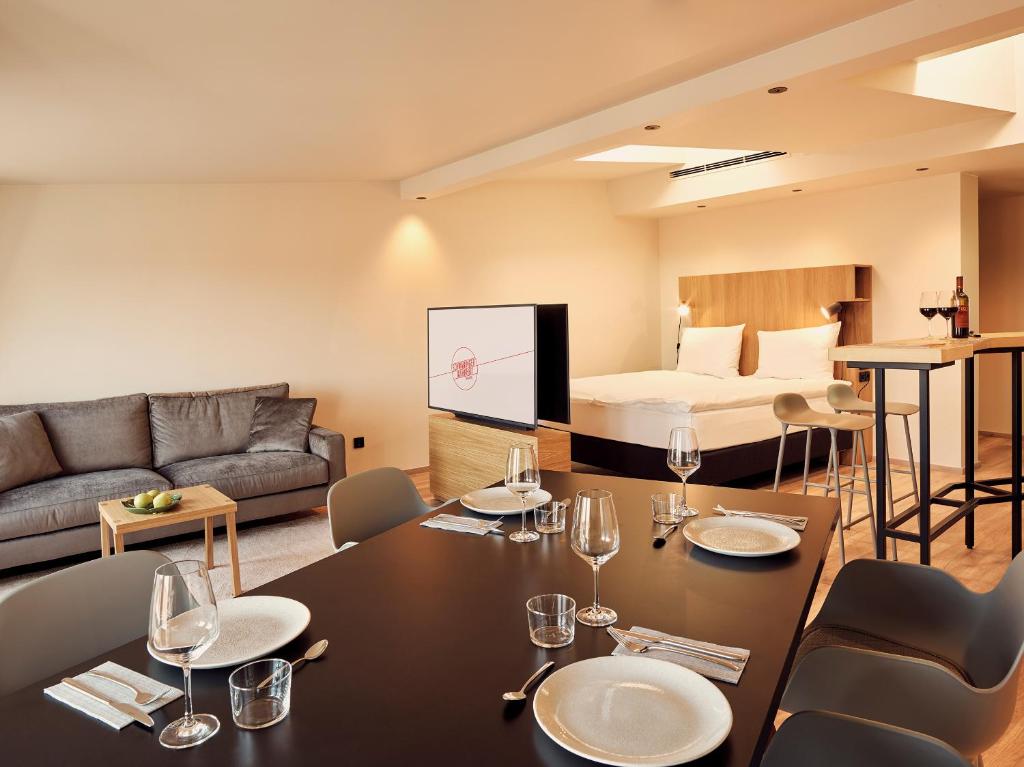 فندق كوسموبوليتان في ميونخ: غرفة معيشة مع طاولة وكراسي وسرير