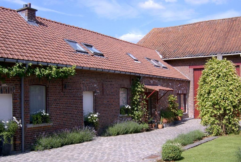 een stenen huis met een rood dak en een oprit bij B&B De Pepelinck in Denderwindeke