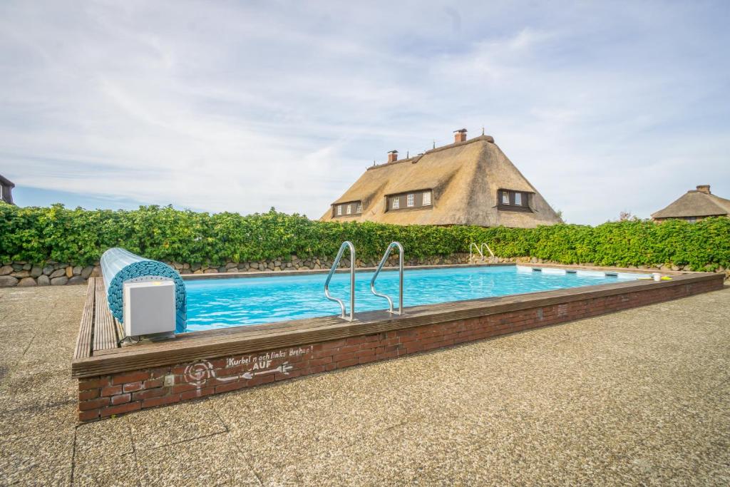 a swimming pool with a house in the background at App. Weißes Kliff in Braderup