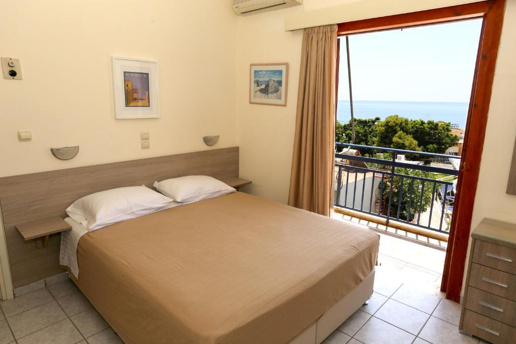 a bedroom with a bed and a large window at Hotel Karyatides in Agia Marina Aegina