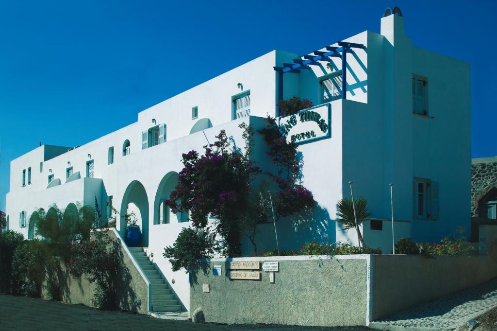 Un grand bâtiment blanc avec des escaliers se trouve juste devant. dans l'établissement King Thiras Hotel, à Fira