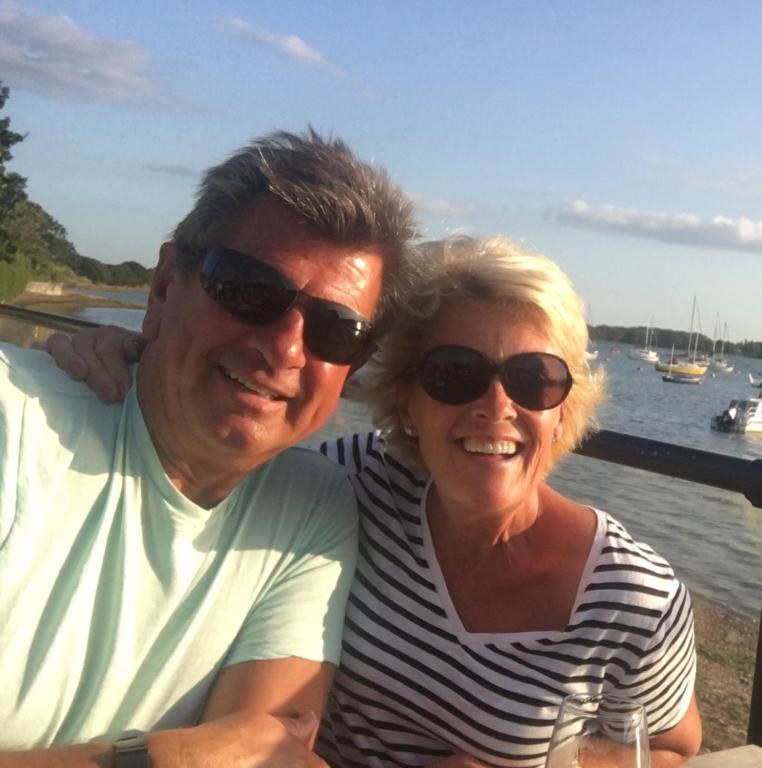 a man and a woman sitting next to the water at Linden House in West Wittering