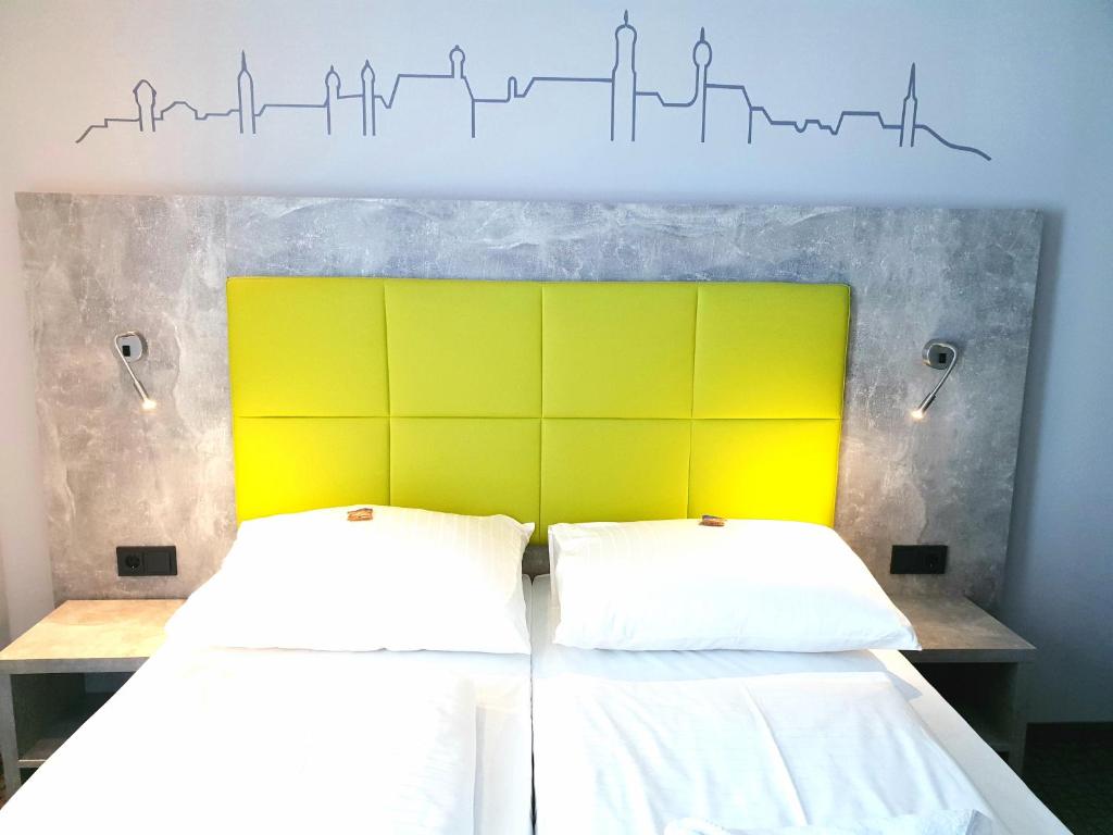 - une chambre avec 2 lits et une tête de lit jaune dans l'établissement SleepySleepy Hotel Dillingen, à Dillingen an der Donau