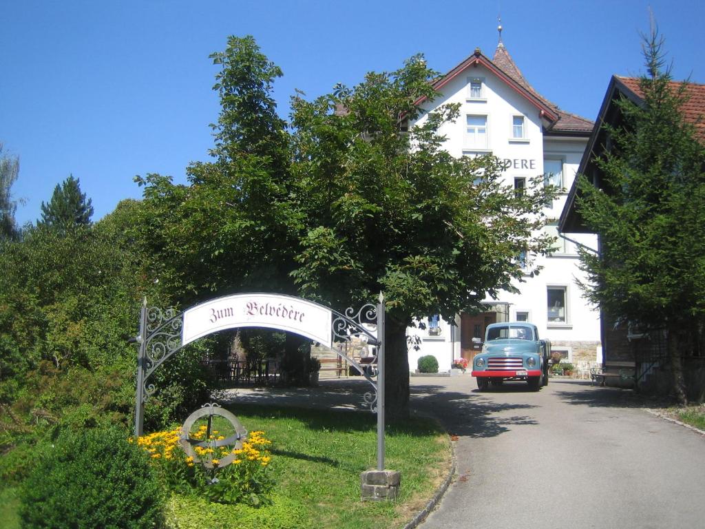 a sign in front of a house with a car at Hotel Restaurant Belvedere in Weissbad