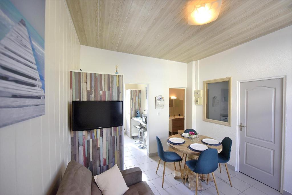 sala de estar con mesa, sillas y TV en Appartement "Mer" - 50m Front de Mer, en Berck-sur-Mer