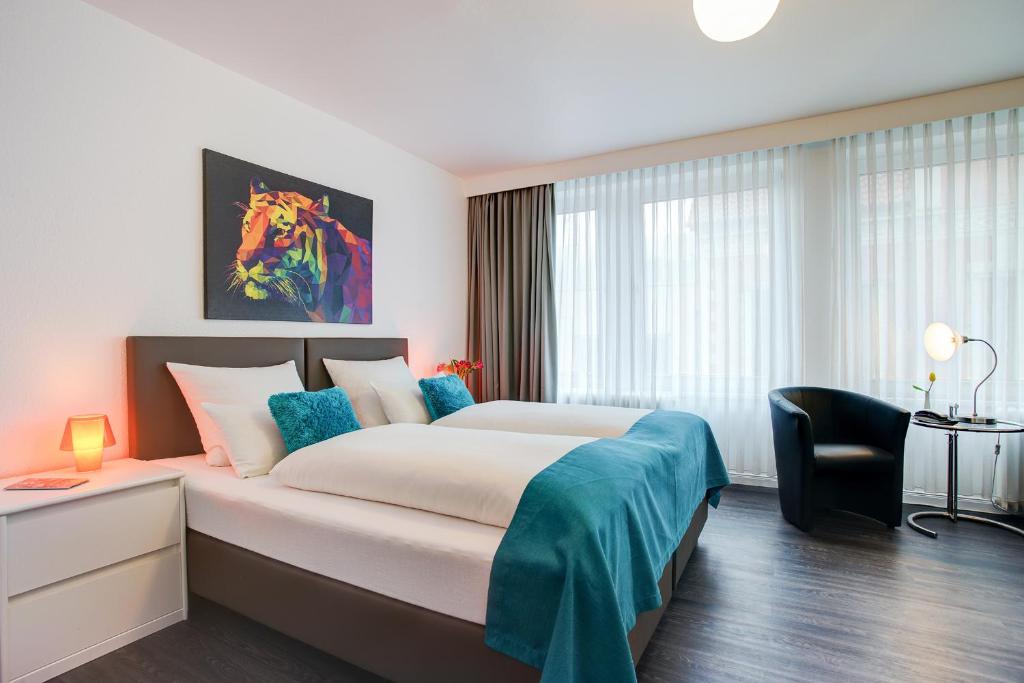 ein Hotelzimmer mit einem großen Bett und einem Stuhl in der Unterkunft Hotel Atlanta in Hannover