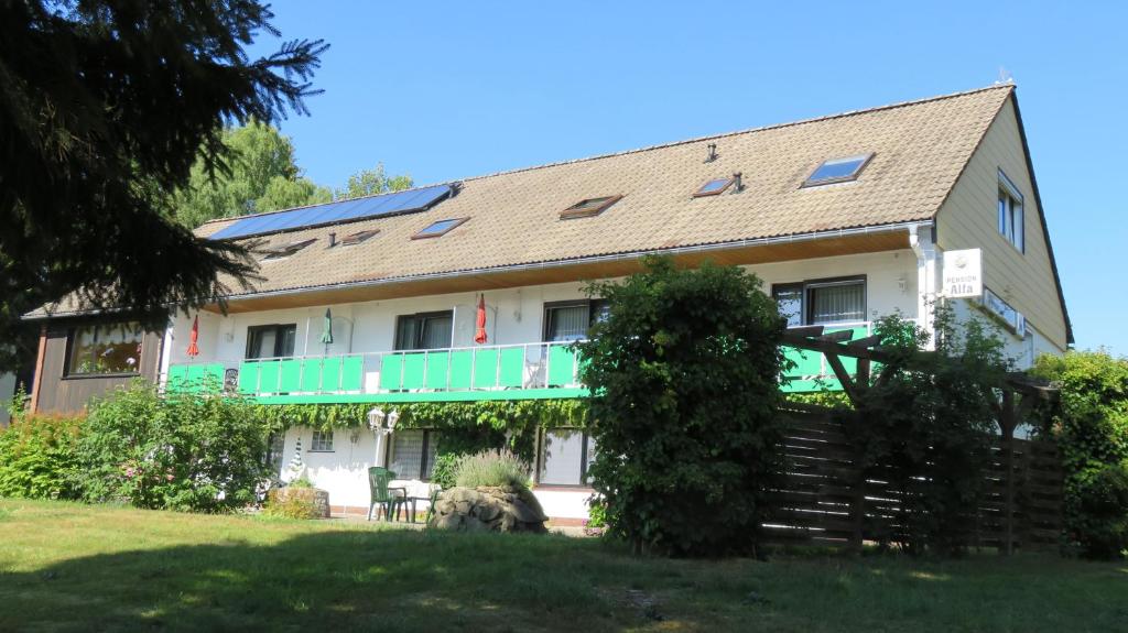 a large house with a green balcony at Pension Alfa in Sankt Andreasberg