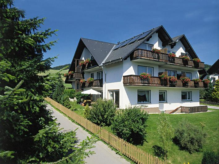 a large white house with a balcony with plants at Haus Kieferneck in Willingen